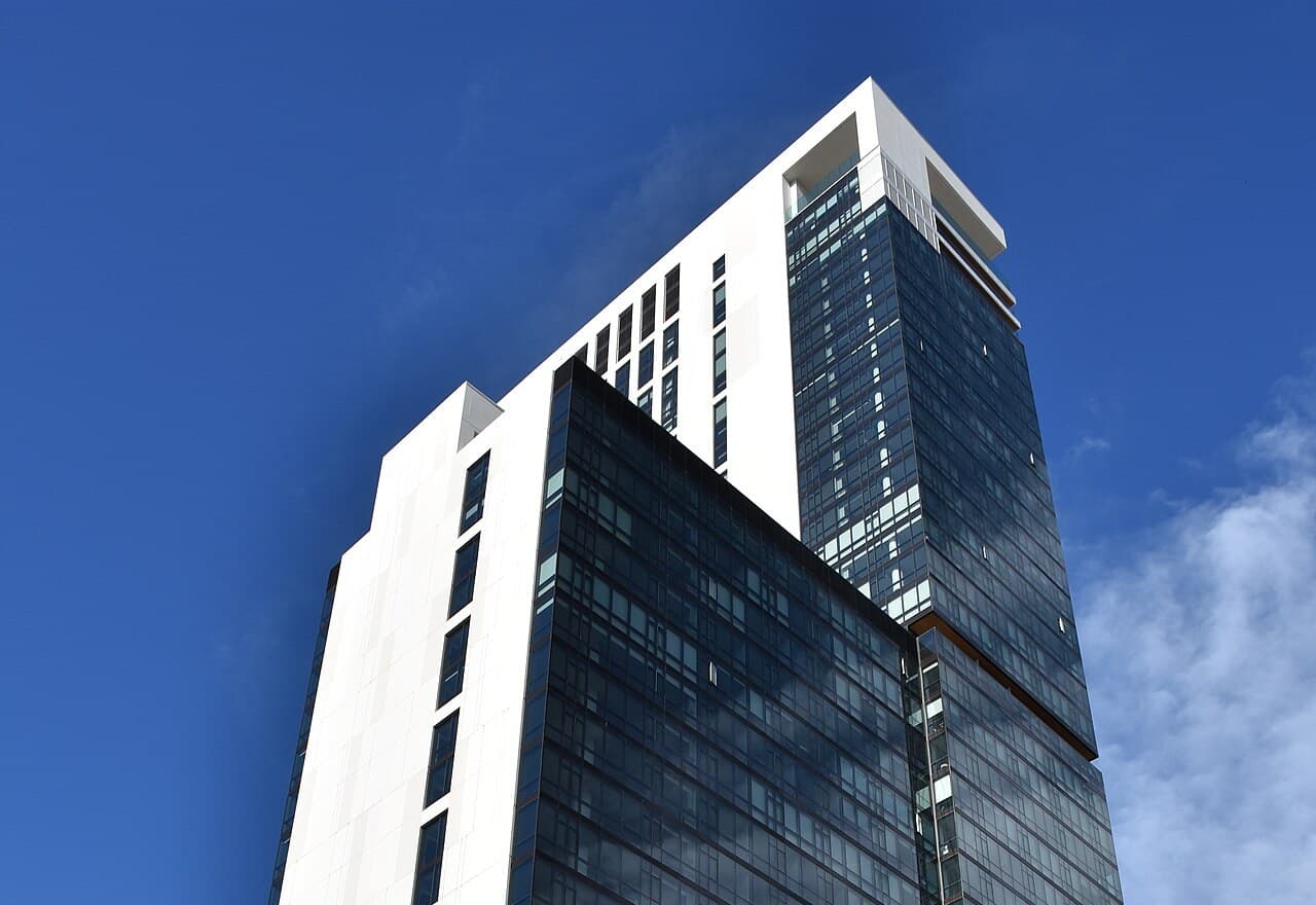 Glass and panel facade of a modern residential high-rise tower against a blue sky
